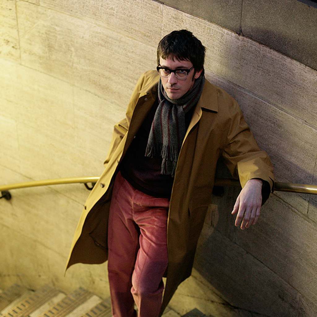 Graham Coxon wearing the Cordings Hampton Mackintosh at the entrance to a London tube station
