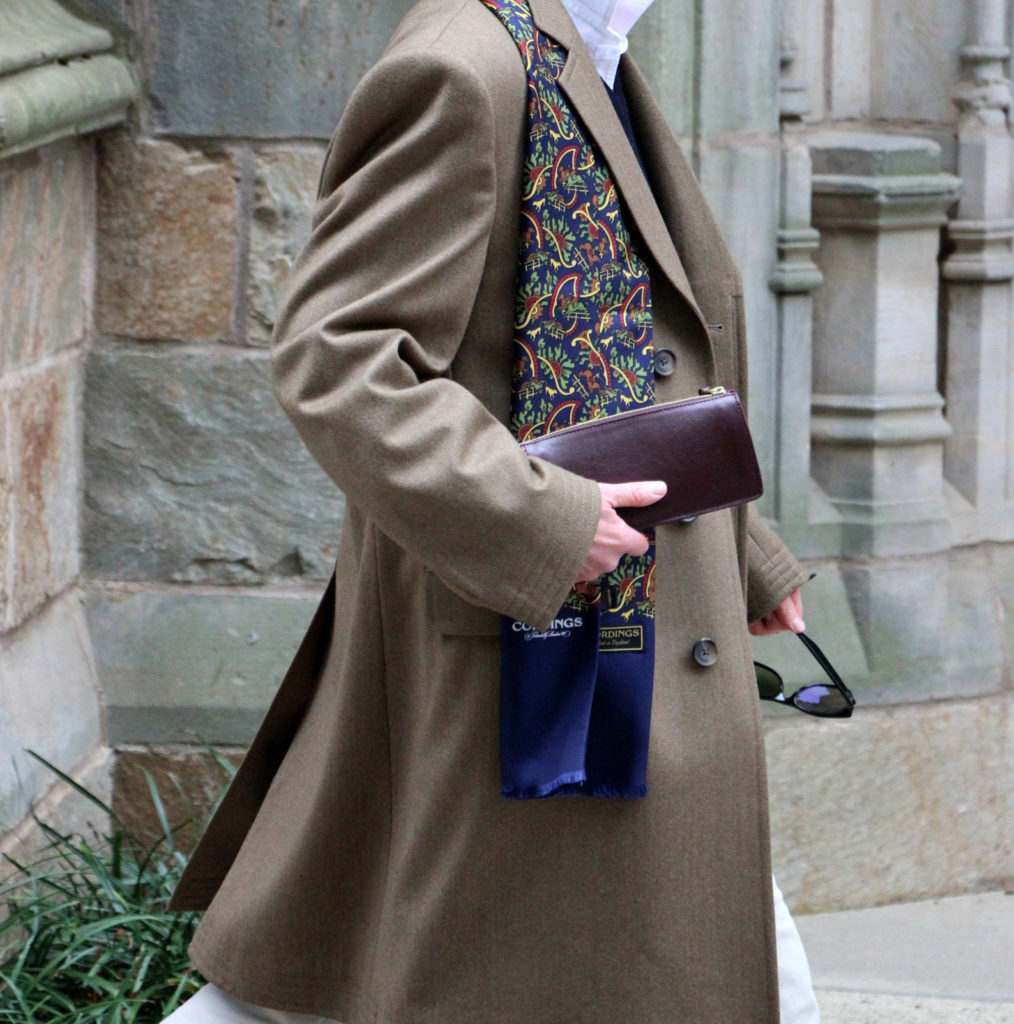 A woman walking through a city wearing a Cordings Covert Coat