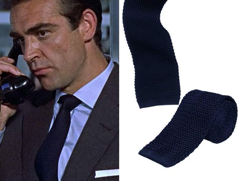 Sean Connery wearing a blue shirt and a blue knitted tie alongside a rolled up knitted tie on a white background