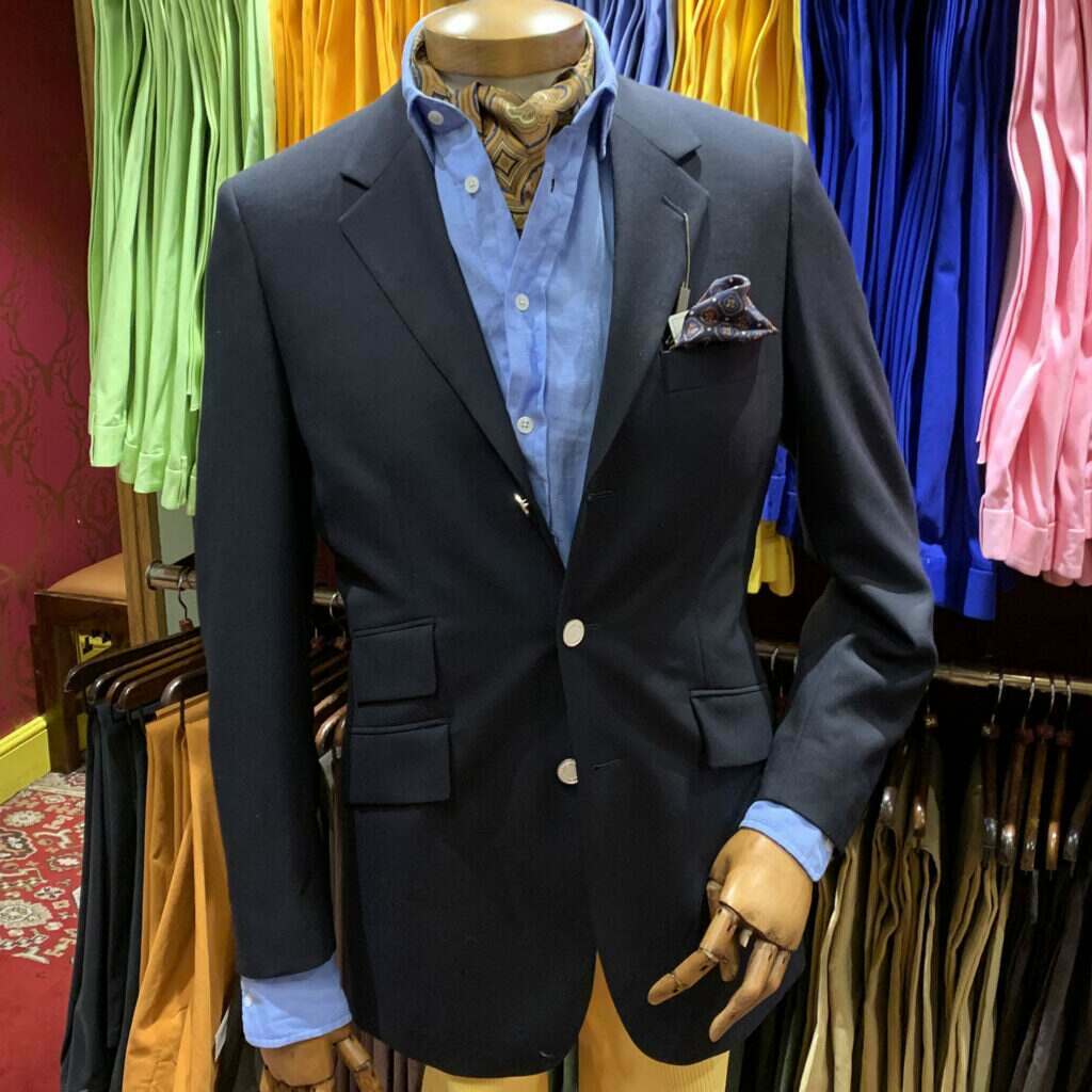 A mannequin stood in Cordings Piccadilly shop dressed in a blue linen jacket, a pale blue linen shirt, a caramel brown cravat and a blue handkerchief in the jacket pocket.