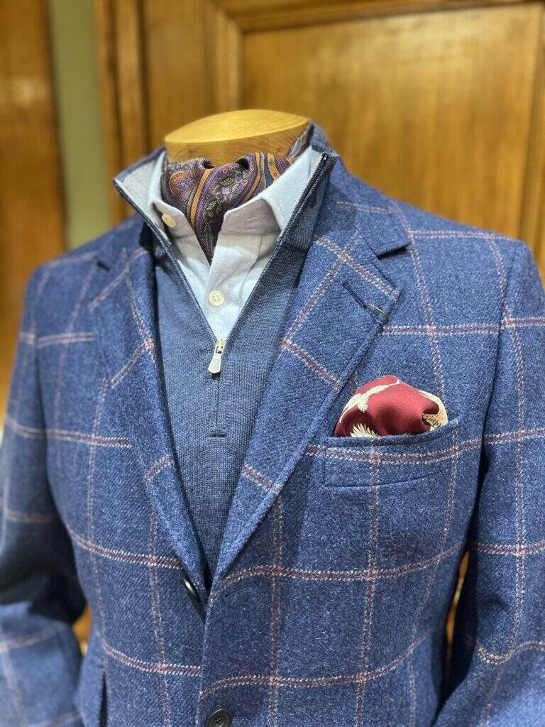 Cordings mannequin wearing a tweed jacket, jumper and pale blue shirt