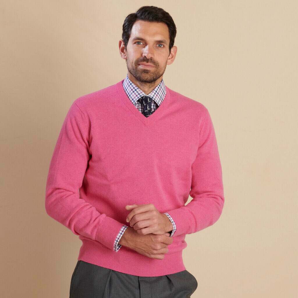 Cordings model in a pink v-neck lambswool wearing a check shirt. 