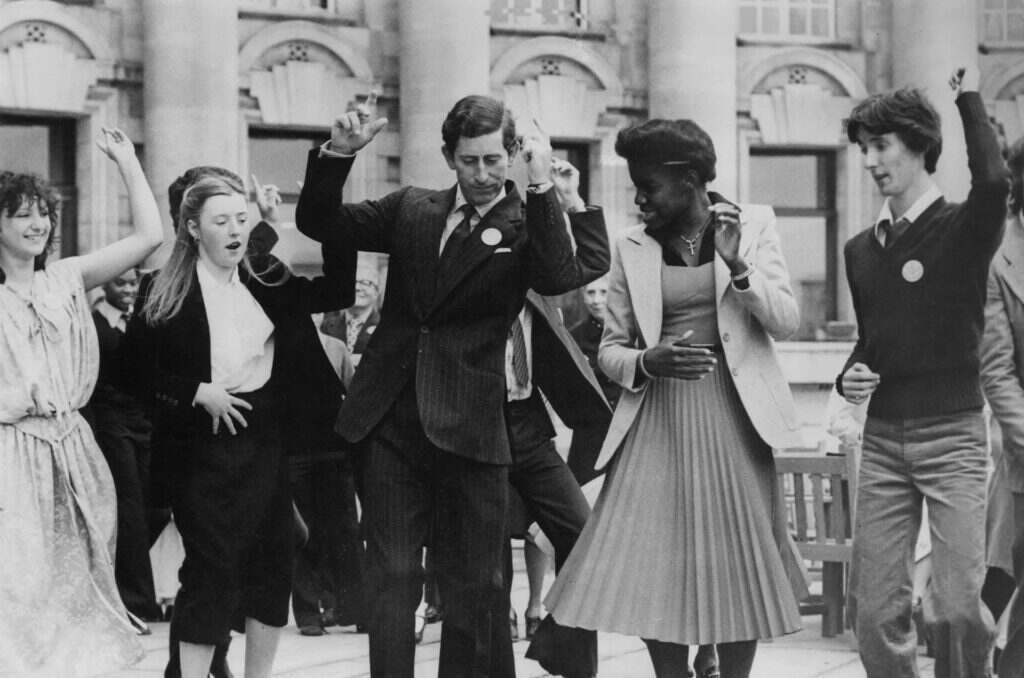 King Charles dancing with others from St George's Secondary School, wearing a suit.